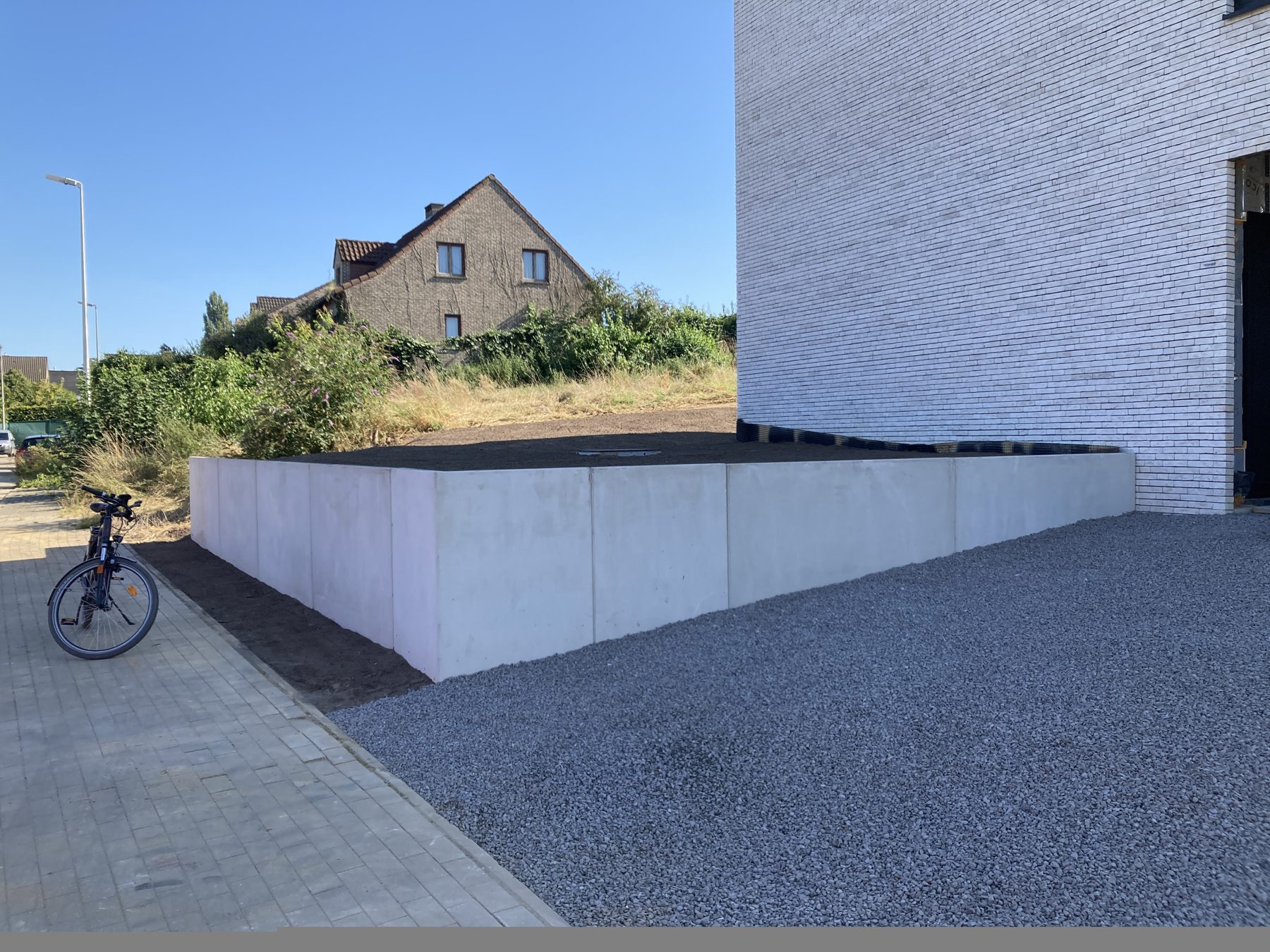 Nieuwe keerwand in beton met grindverharding