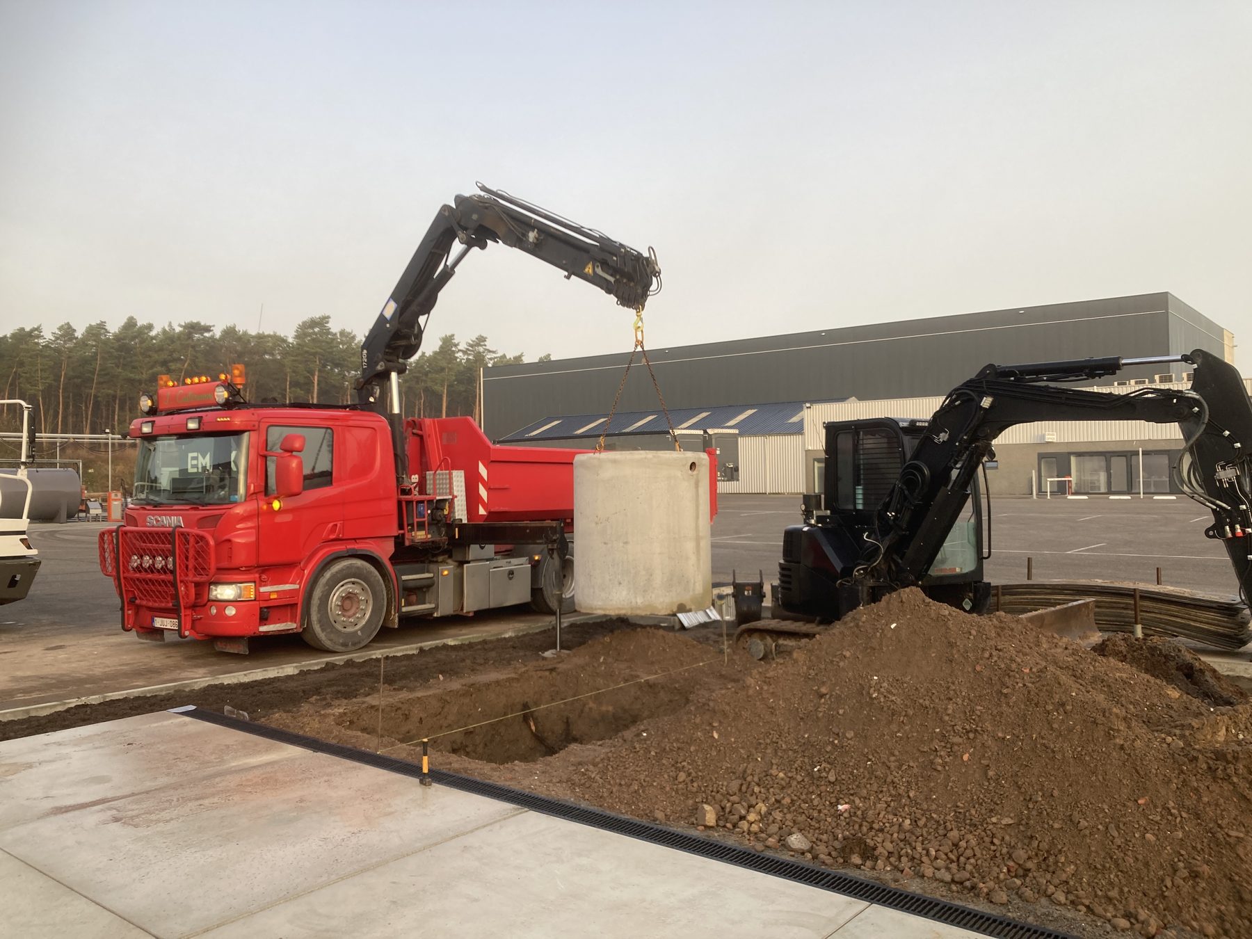 Grondwerken met kraan en kipwagen op een werf