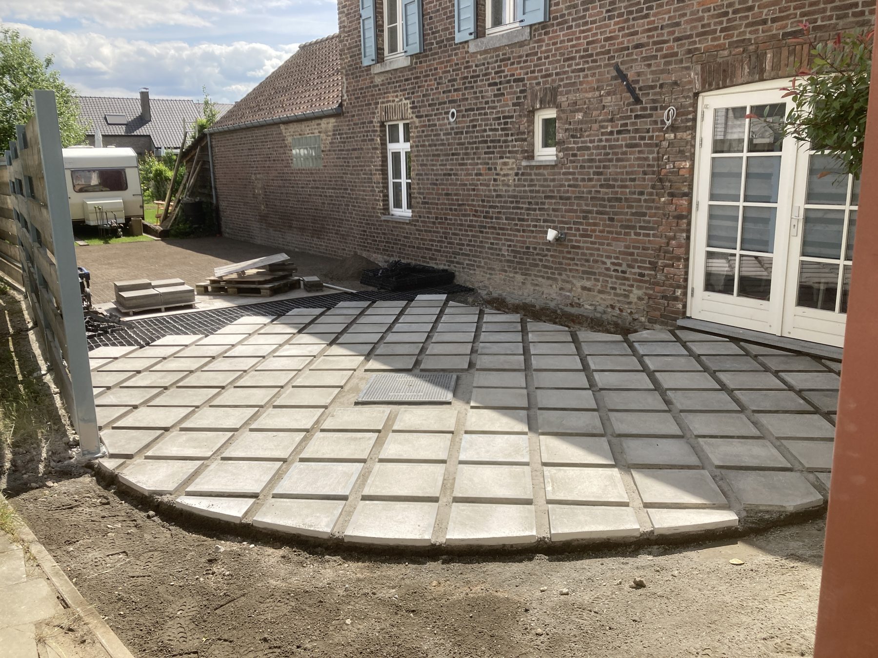 Terras in grote betontegels tegen een woning